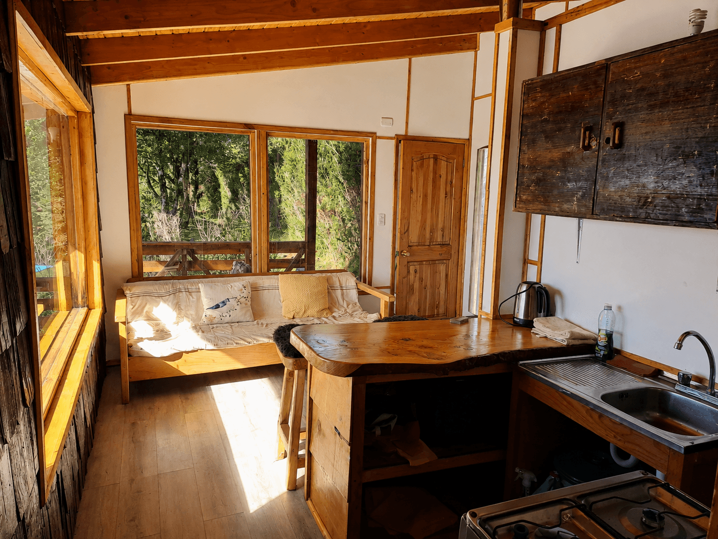 Interior de la cabaña para dos personas, con sofá, barra de madera y cocina