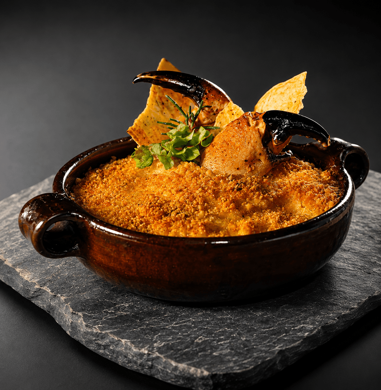 Pastel de jaiba gratinado en paila de greda, con pinzas de jaiba y tostadas